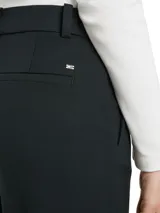 Pantalón negro de vestir, de corte acampanado, con raya marcada en la parte delantera y trasera, bolsillos de ojal y logo esmaltado de Tommy Hilfiger encima del bolsillo trasero.