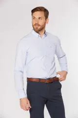 Camisa de manga larga con diseño de rayas finas en color celeste, cuello con botones y bolsillo ojal en el pecho.
