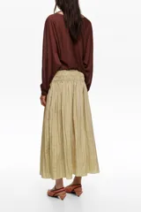 Falda midi de corte en A y silueta fluida, color beige, con diseño de frunces hasta la cadera que aporta movimiento.