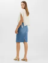Falda de denim en lavado azul medio con efecto de desgaste localizado, de silueta tubo y largo a la rodilla. Presenta tiro medio-alto, pretina con trabillas, cierre frontal con cremallera y botón metálico, bolsillos frontales y costuras verticales que estructuran la prenda.