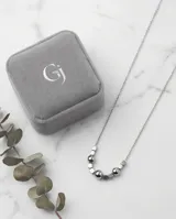 Collar de cadena fina de acero con diseño central compuesto por esferas y cubos metálicos intercalados.