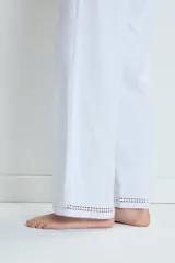 Pijama de dos piezas en color blanco, confeccionado en algodón. Incluye una remera de manga corta con cuello en V y detalles de calados, y un pantalón de corte recto con detalles de calados en el ruedo.