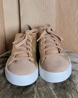 Zapatillas urbanas de cuero metalizado dorado y gamuza beige, con cordones anchos al tono y suela blanca.