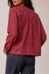 Chaqueta de lino color beige, de corte recto, escote redondo y cierre frontal con broches a presión. Cuenta con mangas largas y costuras decorativas pespunteadas en el frente.