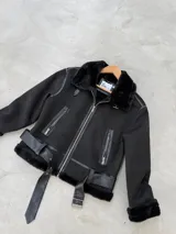Campera tipo gamulán de corte aviador, color negro, confeccionada en gamuza sintética con interior de piel sintética. Presenta cierre frontal, bolsillos laterales con cierre, detalles en cuero sintético y cinturón ajustable en la cintura.