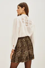 Falda corta plisada con estampado animal print de leopardo, con detalle de volado en el ruedo y cintura elástica.