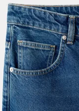 Jeans de corte recto y tiro medio con diseño de cinco bolsillos, trabillas para cinturón y cierre frontal con botón y cremallera.