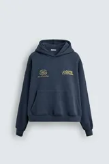 Sudadera tipo hoodie de corte relajado en color azul oscuro con efecto lavado. Presenta capucha, manga larga, bolsillo frontal tipo canguro y detalles estampados en color dorado en el pecho.