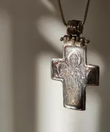 Collar con dije de cruz plateada con la figura de Cristo en relieve.