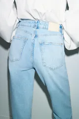 Jeans de tiro alto con corte mom fit, cinco bolsillos y cierre frontal con cremallera y botón.