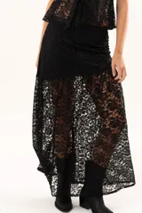 Pollera larga de encaje negro con diseño asimétrico. Presenta un forro interno hasta la altura del muslo y una sección inferior con transparencias que aporta movimiento y fluidez.