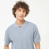 Remera polo celeste de punto con textura en zigzag, manga corta y cuello clásico con tres botones.