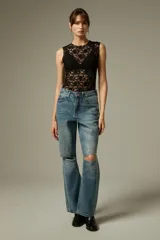 Pantalon de jean azul con corte recto y ancho, presenta aberturas en las rodillas y detalles de tachas metálicas a lo largo de las costuras laterales.