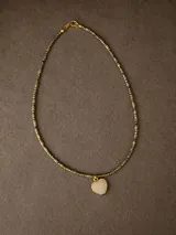 Gargantilla delicada compuesta por pequeñas piedras semipreciosas facetadas en tonos oscuros y dorados, con un dije central en forma de corazón de piedra natural negra enmarcado en metal.