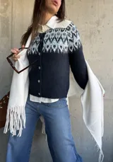 Cardigan de punto en color azul marino con diseño jacquard en tonos celestes y blancos en la parte superior. Presenta cuello redondo, cierre frontal con botones y mangas largas.
