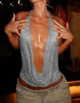 Top de tejido metálico plateado con diseño de cuello halter y escote profundo en V. Presenta una caída fluida y un acabado brillante ideal para eventos nocturnos.