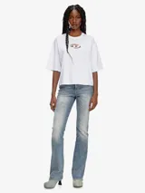 Camiseta blanca de algodón orgánico con corte oversize y forma cuadrada. Presenta un logotipo moderno con efecto 'peekaboo' en el pecho, donde un parche de la 'D' ovalada cortada a láser deja ver la piel.