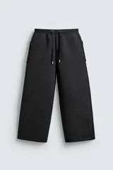 Pantalón de corte wide fit confeccionado en tejido técnico con efecto neopreno. Presenta cintura elástica ajustable con cordón, perneras anchas con costura frontal, bolsillos laterales y bolsillos traseros de plastrón.