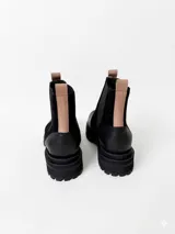 Botas tipo chelsea de cuero, combinando texturas en color bordó. Presentan paneles laterales elásticos en negro, suela track robusta y tiradores en la parte superior.