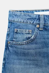 Shorts de denim gris claro con efecto lavado, tiro bajo y corte ancho (baggy). Presenta cinco bolsillos y cierre frontal con cremallera y botón metálico.