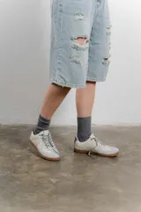 Zapatillas urbanas de cuero color crema con puntera y talón en gamuza gris, suela de goma marrón y cordones grises.