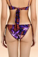 Bombacha de bikini con estampado de hojas en tonos púrpura y cobre, con tiritas laterales ajustables y ribetes decorativos.