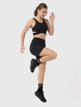 Top deportivo negro de escote redondo, con bandas elásticas cruzadas bajo el busto y abertura en la espalda.