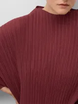 Vestido midi de poliéster reciclado con textura plisada, cuello perkins y mangas amplias redondeadas. Presenta un diseño de corte holgado con un detalle de cambio de textura en el lateral izquierdo.