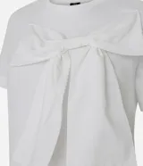 Remera de manga corta confeccionada en algodón, con cuello redondo y diseño recto. Presenta un lazo grande aplicado en la parte frontal que aporta volumen a la prenda.