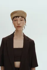 Blazer de manga corta color marrón oscuro, de botonadura sencilla con solapas de muesca, cierre de un botón, bolsillos delanteros ribeteados y forro interior.