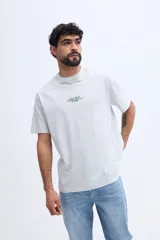 Remera oversize negra de manga corta, con calce amplio y estampa gráfica en la espalda con texto en tonos azules y dorados.