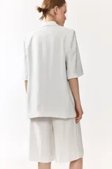 Blazer de botonadura sencilla con solapas de muesca, color blanco, de manga corta, con cierre de un botón y bolsillos delanteros ribeteados, con forro interno en tono tostado.