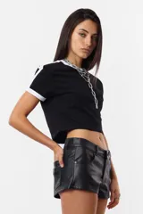 Remera negra de algodón tipo baby tee, mangas cortas con detalles en blanco en hombros y terminaciones. Estampa frontal con texto blanco.