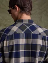 Camisa de manga larga en color azul noche con un patrón de cuadros finos en tonos rojos y verdes. Presenta cuello clásico, cierre frontal con botones y un bolsillo en el pecho con solapa.