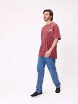 Remera de algodón con calce oversize, color negro con efecto lavado. Presenta un estampado gráfico en la espalda con diseño de espiral en tonos rosado y celeste, acompañado de inscripciones decorativas.