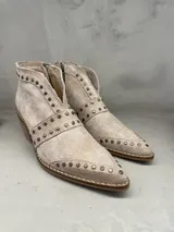 Bota corta de cuero color beige con tachas doradas, cierre interno y taco de 5 cm.