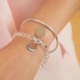 Brazalete tipo esclava de alambre redondo en plata 925, con dije de medalla circular colgante.