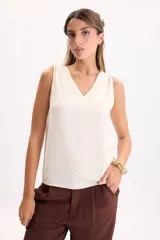 Musculosa con escote en V color crudo, confeccionada en tejido airflow liviano, de corte suelto y sisas amplias.