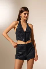 Top estilo corset de cuero sintético negro, con escote halter profundo y cierre frontal con alamares.