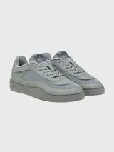 Zapatillas Diesel modelo S-Oval Skate, color gris claro, con plataforma gruesa y detalles en diferentes texturas de material sintético y tela. Presentan cordones y un dije metálico con el logo de Diesel en la parte frontal.