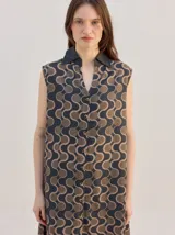 Vestido camisero midi de algodón, sin mangas, con cuello clásico en contraste y cierre frontal con botones. Presenta un estampado geométrico con patrón psicodélico de ondas.