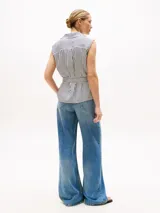 Blusa sin mangas con cuello camisero y diseño cruzado a rayas verticales blancas y azules.