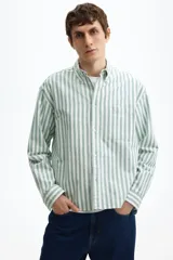 Camisa de manga larga de algodón Oxford con patrón de rayas verticales en color verde y blanco, cuello americano, cierre frontal de botones y un bolsillo aplicado en el pecho.