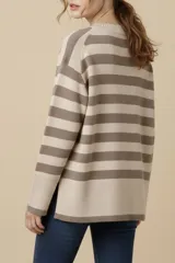 Sweater de punto a rayas horizontales negras y crudas, con cuello redondo y mangas largas. Tiene ribete marrón en puños y ruedo.