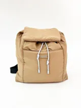 Mochila color camel con cierre superior con solapa y cordón ajustable. Tiene un bolsillo frontal con cierre y etiqueta con el logo de la marca. Las correas son negras y ajustables.