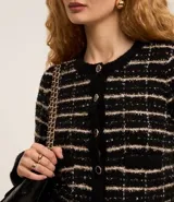 Cardigan cropped negro con diseño de tweed a cuadros blancos, con cuello redondo y cierre frontal con botones esmaltados.