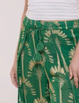 Pantalón palazzo verde de gasa con sutil transparencia y estampa metalizada dorada. Presenta cintura elastizada con cordón ajustable terminado en borlas y diseño de piernas anchas cruzadas en el frente con terminación de puntilla en los bordes.