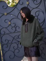 Buzo color crudo con cuello de piel sintética color crema, abertura parcial con cierre de cuero marrón y hebilla dorada, puños con ajuste de cuero marrón y bolsillos laterales.