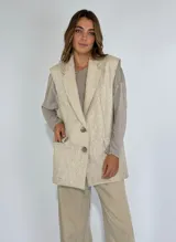 Chaleco largo color crudo con solapas, sin mangas y cierre con dos botones.