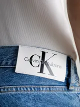 Jeans de denim rígido azul medio con lavado a la piedra, talle medio a bajo y pierna recta larga. Presenta diseño de cinco bolsillos y bragueta con cremallera.